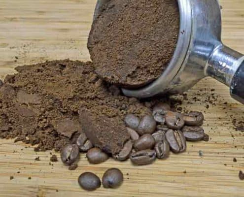 A coffee grinder and some beans on the ground