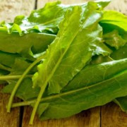 A pile of green leafy vegetables on top of a wooden table.