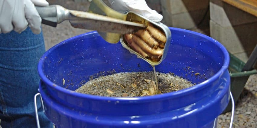 A person is using tongs to stir something in a bowl.