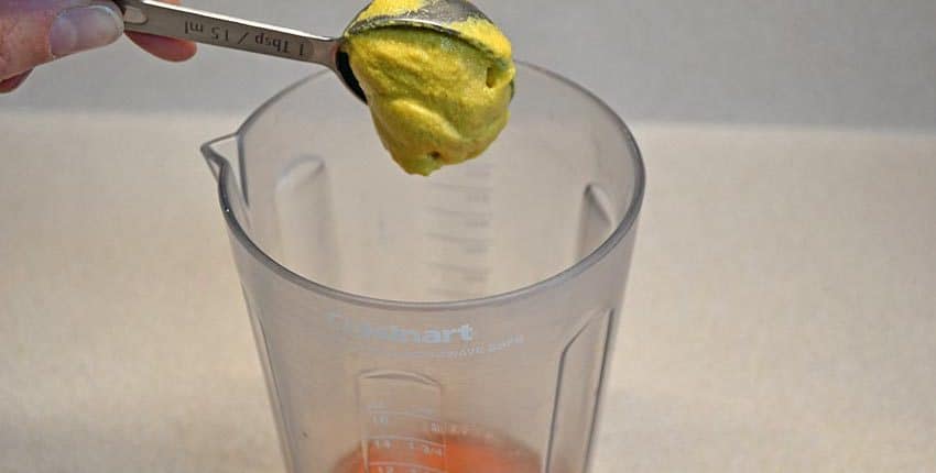 A spoon is holding up an orange to be stirred.