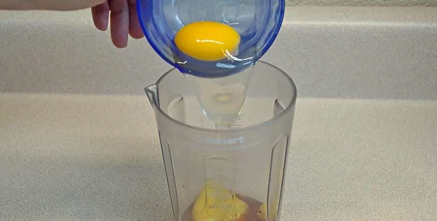 A person is pouring lemon juice into a glass.