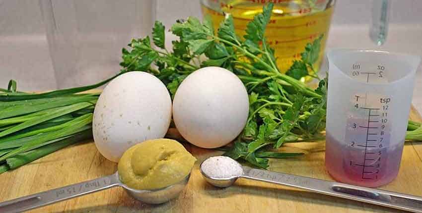 A table with eggs, lemon and greens on it.