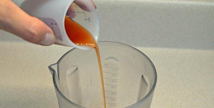 A person pouring liquid into a measuring cup.