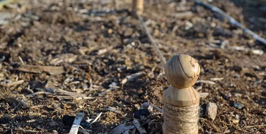 A wooden statue in the middle of some dirt.