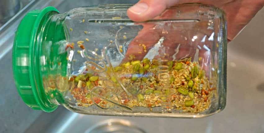 A person holding a container of food in front of the sink.