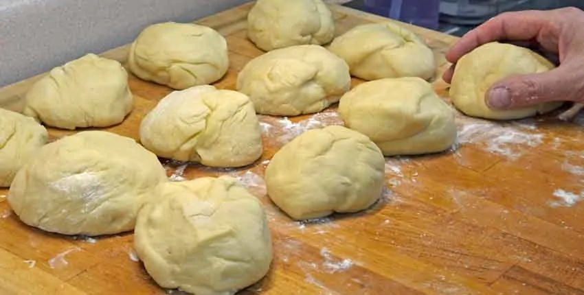 A wooden table topped with lots of dough balls.