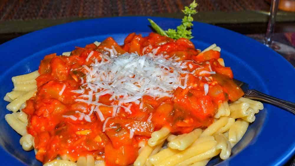 A plate of pasta with sauce and parmesan cheese.