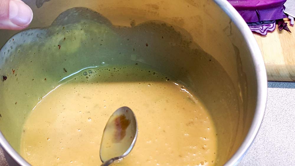 A bowl of soup with spoon in it.